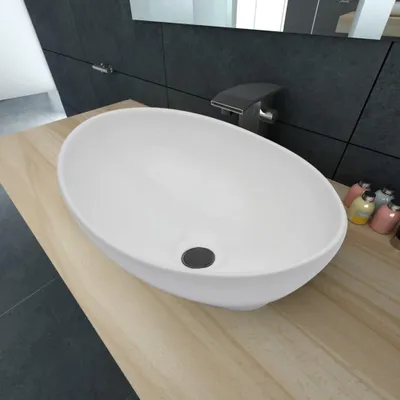 A white oval ceramic sink on a wooden countertop in a modern bathroom.