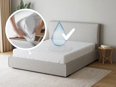 A bed with a white mattress protector and a water drop graphic indicating waterproofing.
