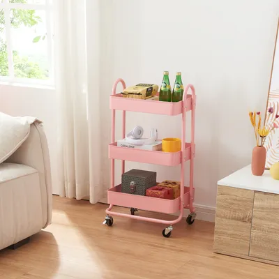 A pink three-tiered rolling cart filled with various items, placed in a room next to a sofa and a cabinet.