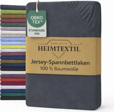 A folded bed sheet is shown next to a stack of other bed sheets in various colors. A tag and a band with product information are attached to the main bed sheet.