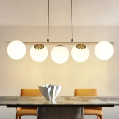 A modern chandelier with five glass globes hangs above a dining table.