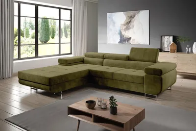 A modern living room with a large green sectional sofa, a coffee table, and a large window with a view of trees.