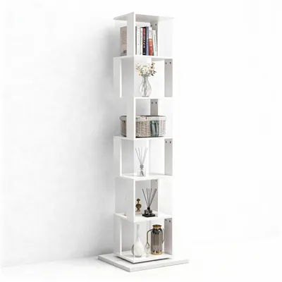 A tall, white, rotating bookshelf with several shelves, each holding decorative items and books, set against a plain white wall.