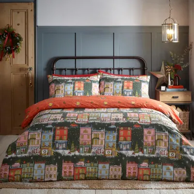 A bed with Christmas-themed bedding in a bedroom setting.