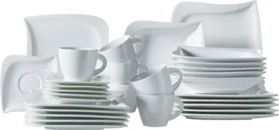 A collection of white ceramic dinnerware, including plates, bowls, and cups, neatly stacked and arranged.