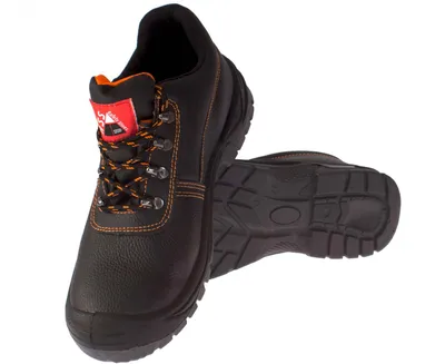 A pair of black safety shoes with orange laces and stitching, presented on a white background.