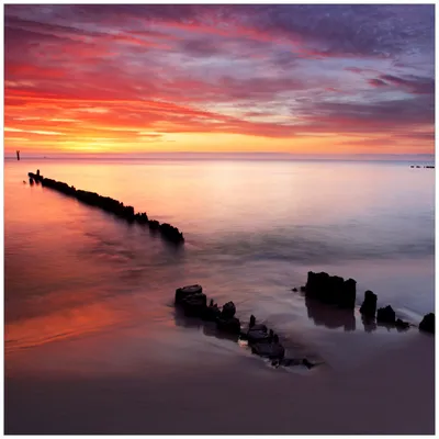 Produktbild von Wallario Premium Glasbild, freischwebende Optik, kräftige Farben, Größe 50 x 50 cm Motiv Sandstrand im Sonnenuntergang - Roter Himmel