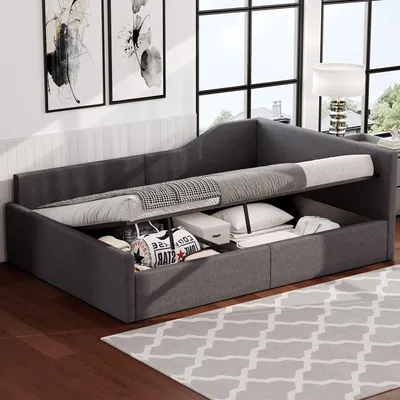 A grey upholstered daybed with storage compartments is shown in a room with large windows and artwork on the wall.