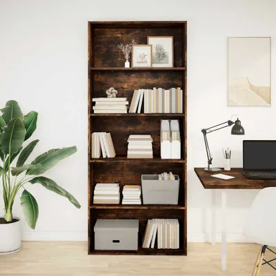 A tall, dark wood bookshelf filled with books and decorative items, next to a desk with a laptop and lamp.