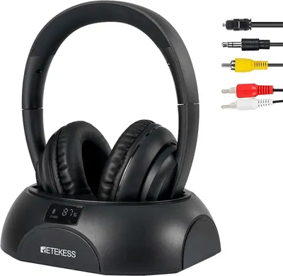 A black wireless headphone set with its charging base and various audio cables.