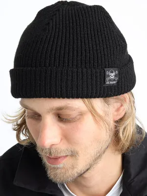 A man wearing a black beanie with a skull and crossbones logo.