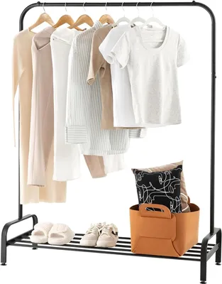 A clothing rack with several garments hanging on it, along with a basket of pillows and shoes on the bottom shelf.