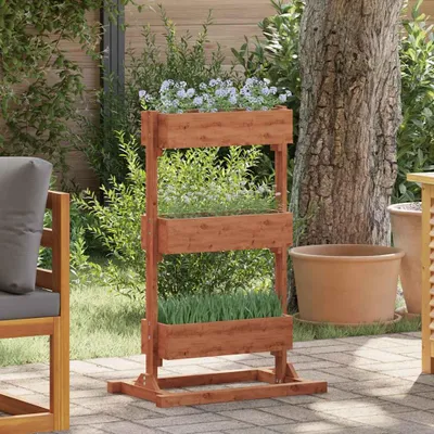 A wooden tiered planter filled with plants and flowers, placed on a patio next to a chair and a tree.