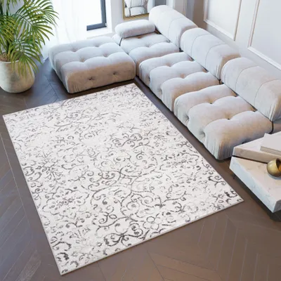 A modern living room with a sectional sofa and a patterned rug.