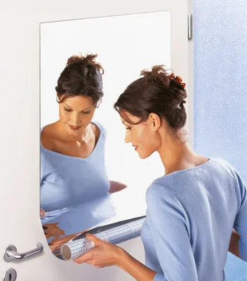 A woman is applying a roll of reflective film to a door.
