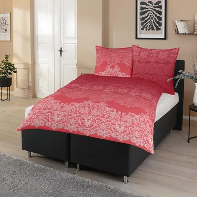 A bed with red and white patterned bedding is shown in a room.