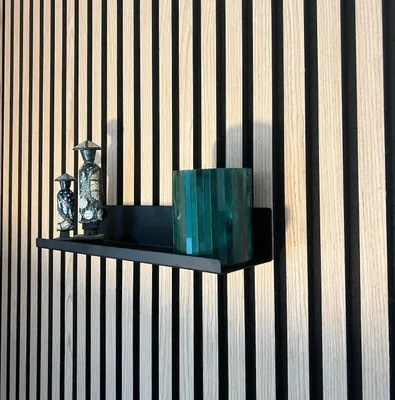 A black metal shelf mounted on a slatted wooden wall, displaying decorative items.