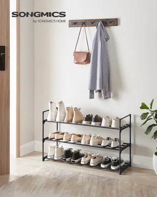 A shoe rack with shoes, a coat, and a purse in an entryway.