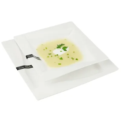 Two square white plates, one stacked on top of the other, with the top plate containing soup and a garnish.