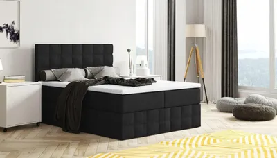 A black upholstered bed with a mattress and pillows in a well-lit bedroom with a large window.
