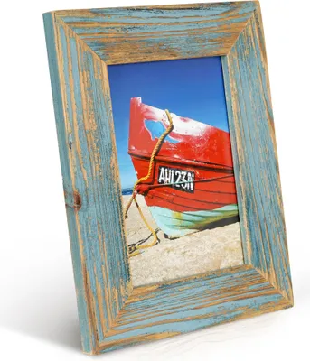A framed picture of a red and blue boat on a sandy beach under a blue sky.