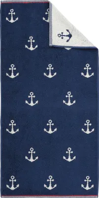 A folded navy blue towel with a pattern of white anchors, with a small section of the reverse side showing.