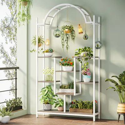 A multi-tiered plant stand filled with various plants and decorative items, placed on a balcony or patio.