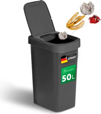 A dark gray Novaliv 50L trash can with its lid open, showing waste items being thrown into it. The product has a 'Made in Germany' label and a green label with 'Novaliv 50L'.