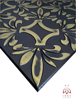 A close-up, angled view of a black and gold embossed decorative panel, likely for walls or ceilings, with a white background.