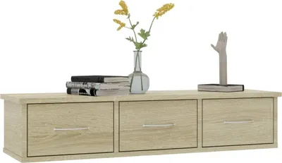 A wooden wall-mounted drawer unit with decorative items on top.