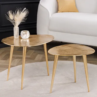 Two gold coffee tables are placed on a rug in front of a white sofa.