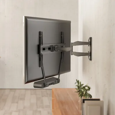 A TV wall mount holding a TV, with a soundbar attached below.