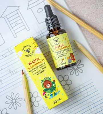 A product shot of a children's vitamin C supplement with its packaging, set against a background of children's drawings and colored pencils.