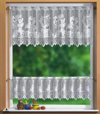 A window with lace curtains featuring teddy bears, with a blurred green background of foliage outside. A few small decorative items are on the windowsill.