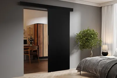 A modern bedroom with a sliding door separating it from a home office.