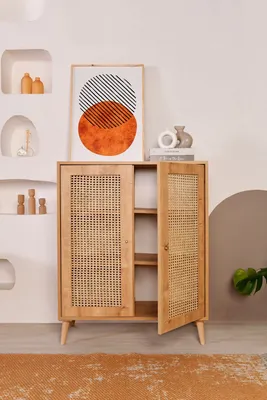 A wooden sideboard with rattan doors is displayed in a room with decorative elements on the wall.
