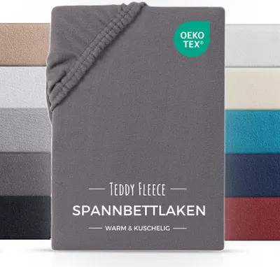 A close-up of a folded grey fitted sheet with a swatch of other colors behind it.