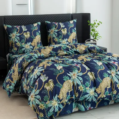 A bed with a duvet cover and pillows featuring a jungle print with leopards.