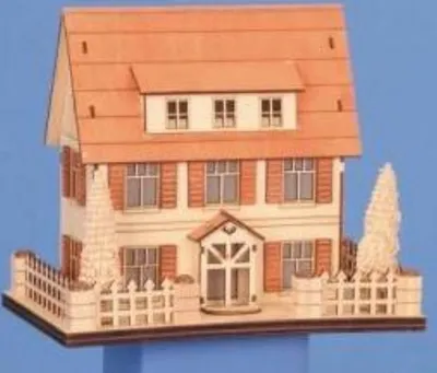 Detailliertes Holzmodell eines zweistöckigen Hauses mit Giebeldach weißen Fensterläden und Vorgarten