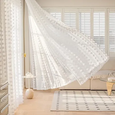 A bright, airy living room with white sheer curtains blowing gently in the breeze.