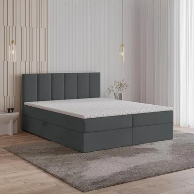 A bedroom scene with a bed, rug, and wall decor.