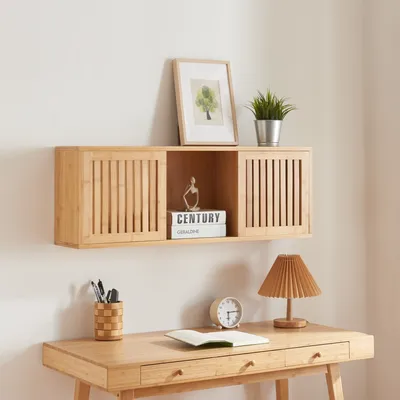 A wooden wall shelf with two sliding doors, decorated with a framed picture, a plant, and books. Below the shelf is a wooden desk with a lamp, a clock, and a notebook.