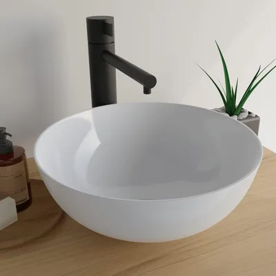 A white round vessel sink with a black faucet is shown on a wooden countertop.