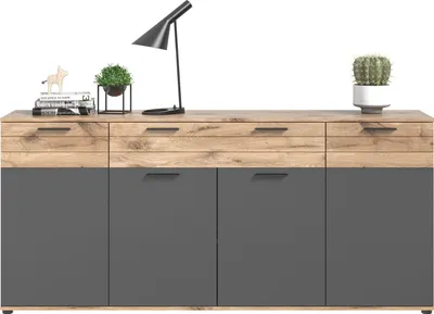 A sideboard with drawers and doors, decorated with a lamp and plants.