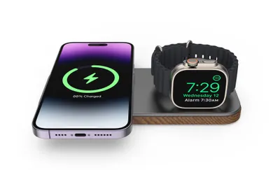 A wireless charging stand with an iPhone and an Apple Watch on it, both charging.