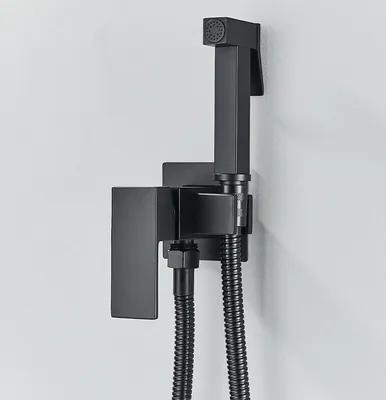 A black bidet sprayer and holder mounted on a light gray wall.