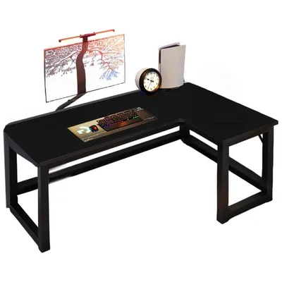 A black L-shaped computer desk with a monitor, keyboard, mouse, clock, and a game console.