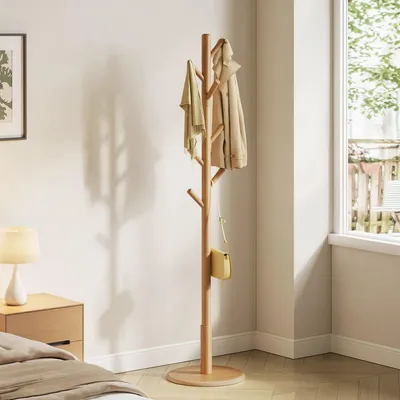 A wooden coat rack with jackets and a bag hanging on it, placed in a room with a nightstand and a lamp.