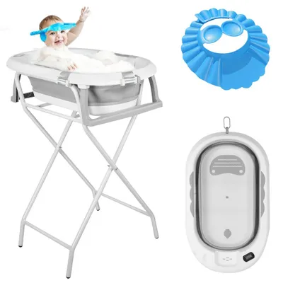 A baby is taking a bath in a portable baby bathtub on a stand, with a shower cap and a folded bathtub shown separately.