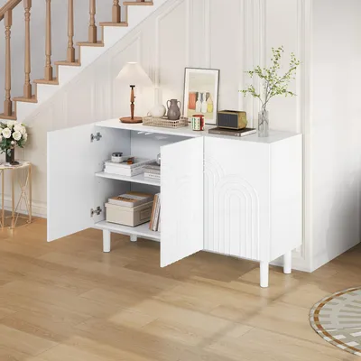 A white sideboard with open doors, revealing shelves with books and decorative items, placed in a hallway next to a staircase.
